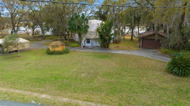 view of front facade with an outdoor structure, a garage, a front yard, and driveway