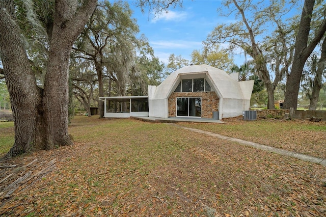 back of house featuring cooling unit, a lawn, and a sunroom