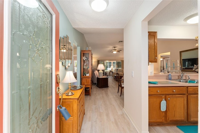 hallway with light wood-style flooring, a sink, and a textured ceiling