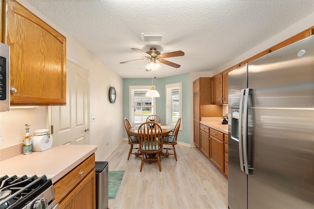 kitchen featuring light countertops, stainless steel fridge with ice dispenser, light wood-style floors, visible vents, and a ceiling fan