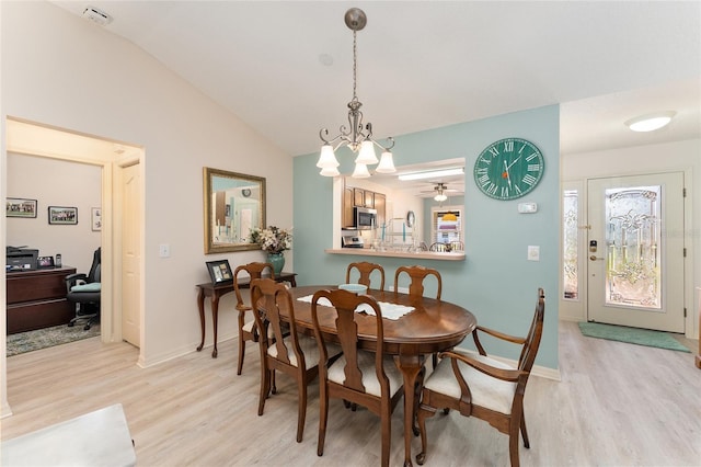 dining area with baseboards, lofted ceiling, ceiling fan with notable chandelier, and light wood finished floors