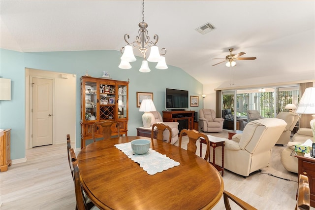 dining area featuring vaulted ceiling, ceiling fan with notable chandelier, baseboards, light wood finished floors, and visible vents