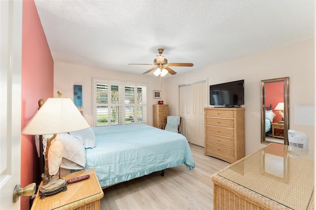 bedroom featuring a closet, a textured ceiling, light wood-style floors, and ceiling fan