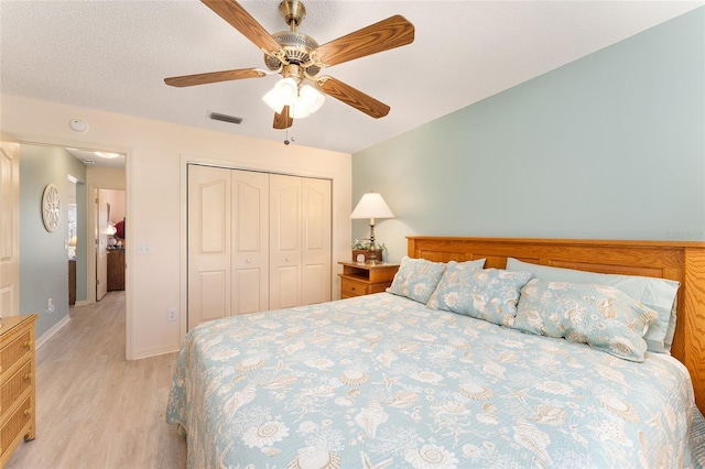 bedroom with a closet, light wood-style flooring, baseboards, visible vents, and ceiling fan
