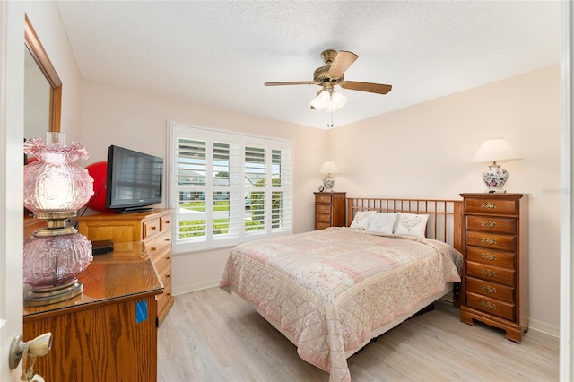 bedroom featuring light wood-style flooring, baseboards, ceiling fan, and a textured ceiling