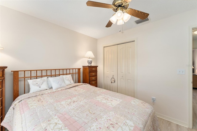 bedroom with baseboards, ceiling fan, visible vents, a closet, and wood finished floors