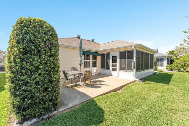 back of property featuring a lawn, a sunroom, roof with shingles, and a patio