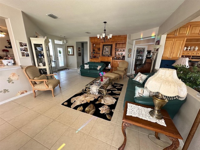 living room featuring visible vents, baseboards, light tile patterned flooring, a textured ceiling, and a chandelier