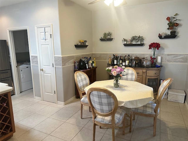 dining space with light tile patterned floors, wainscoting, washer / clothes dryer, and ceiling fan
