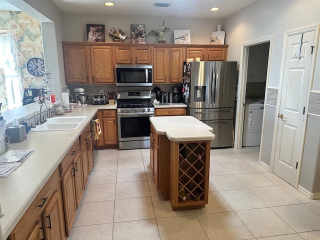 kitchen featuring light tile patterned floors, brown cabinets, appliances with stainless steel finishes, and a sink