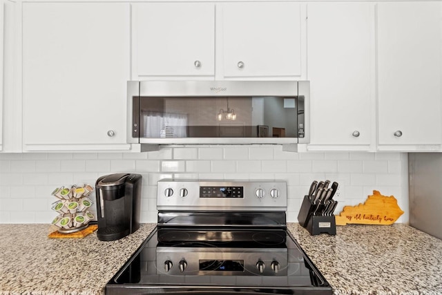 kitchen featuring white cabinetry, decorative backsplash, light stone countertops, and stainless steel appliances