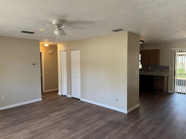 unfurnished room with visible vents, ceiling fan, dark wood-type flooring, and baseboards