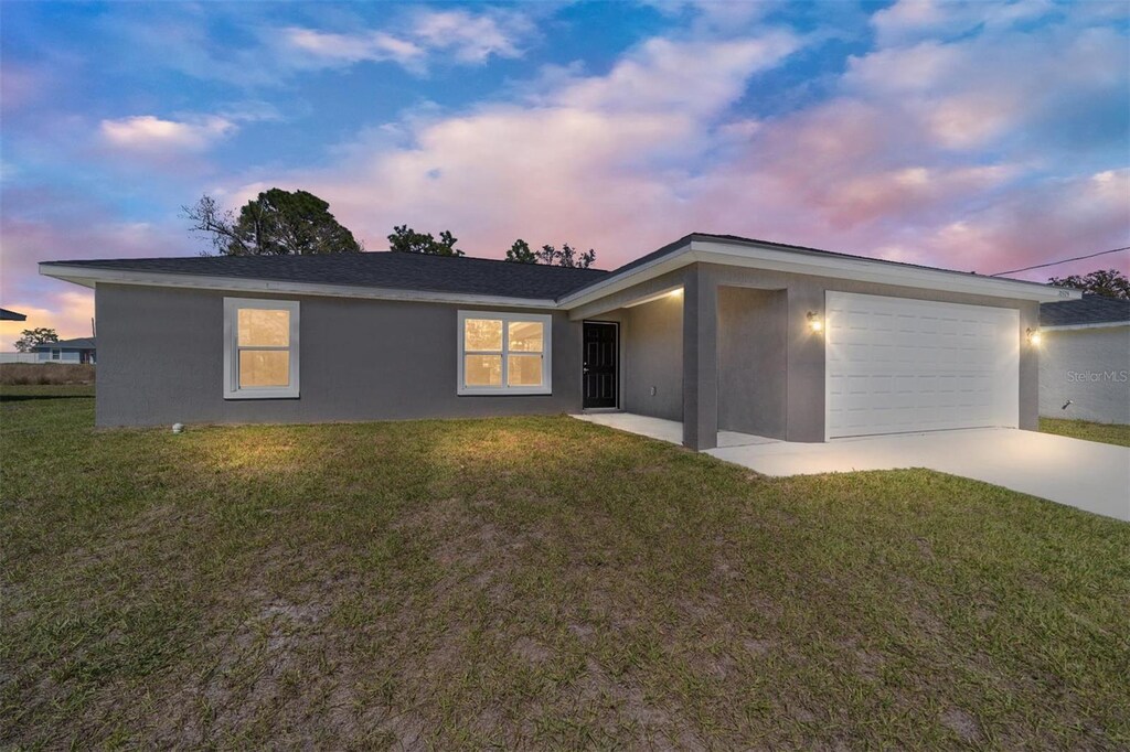 10351 SE 126th St, Belleview, FL 34420 - view of front of house with stucco siding, driveway, a garage, and a yard