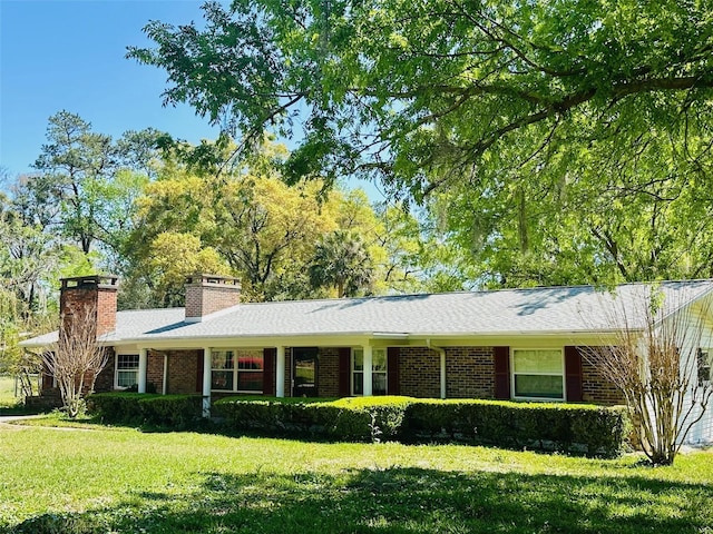 ranch-style house featuring brick siding, a chimney, and a front lawn