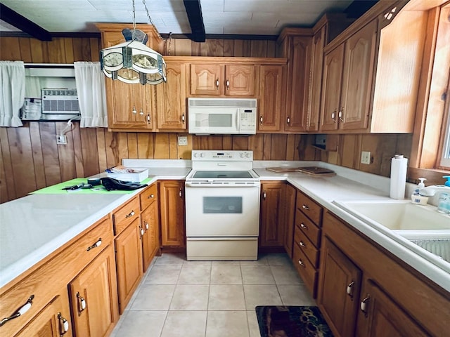 kitchen with brown cabinets, white appliances, wooden walls, light tile patterned flooring, and light countertops