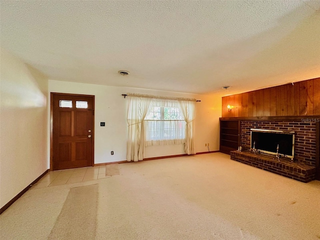 unfurnished living room with baseboards, carpet floors, a textured ceiling, and a brick fireplace