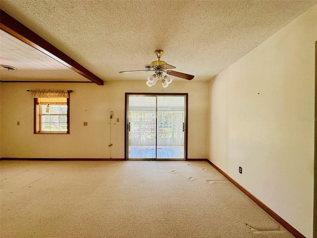 spare room featuring a textured ceiling, beamed ceiling, plenty of natural light, and light carpet