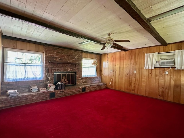 unfurnished living room with wooden walls, a brick fireplace, brick wall, and carpet flooring