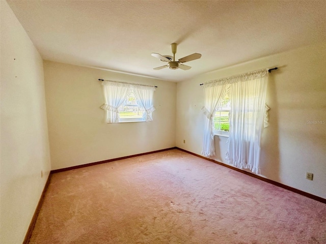 carpeted spare room featuring baseboards, a textured ceiling, and a ceiling fan