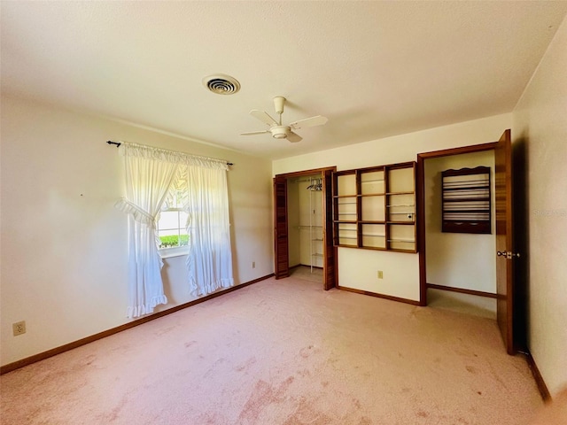 unfurnished bedroom with ceiling fan, baseboards, visible vents, and light carpet