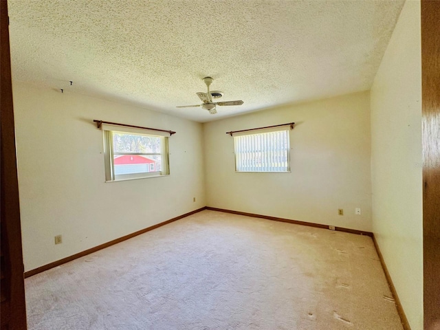 unfurnished room featuring a healthy amount of sunlight, a textured ceiling, carpet, and baseboards