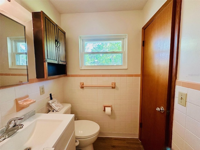 bathroom featuring toilet, vanity, wainscoting, wood finished floors, and tile walls