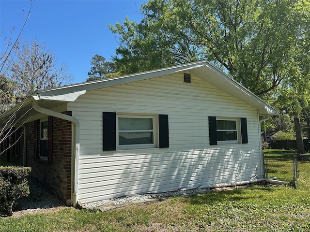 view of side of home featuring brick siding and fence