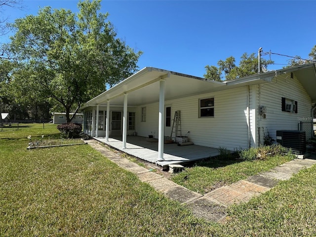 back of house with cooling unit, a lawn, and fence