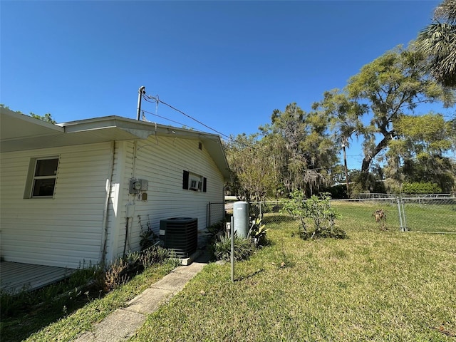 view of home's exterior with central air condition unit, a yard, and fence