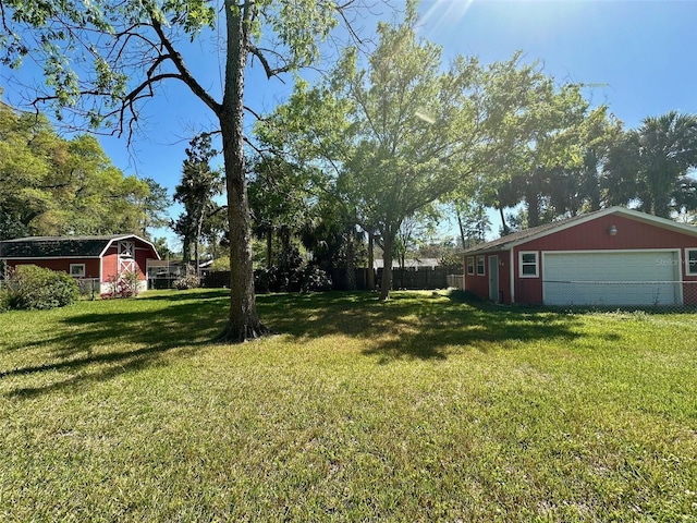 view of yard featuring an outdoor structure, fence, and a detached garage