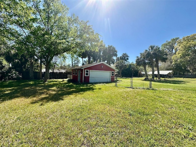 view of yard with an outbuilding, a detached garage, and fence