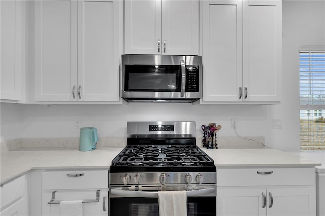 kitchen featuring white cabinets, light stone counters, and appliances with stainless steel finishes