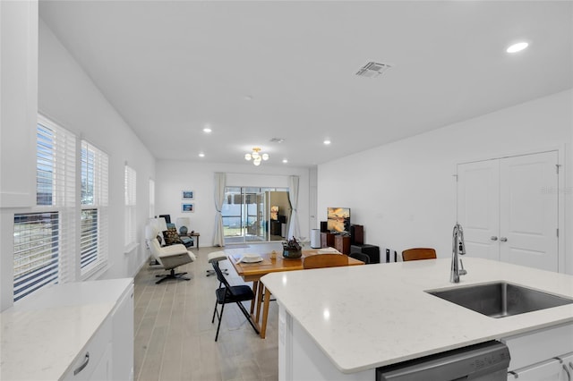 kitchen featuring a wealth of natural light, white cabinets, dishwasher, and a sink