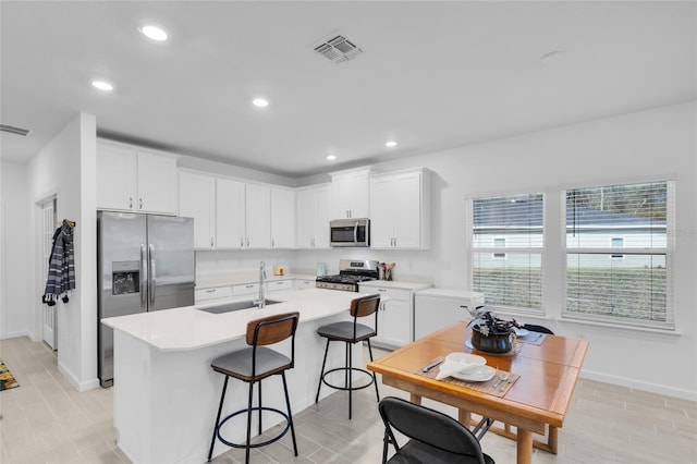 kitchen with visible vents, a center island with sink, light countertops, appliances with stainless steel finishes, and a sink