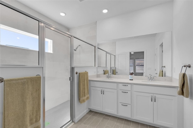 bathroom with double vanity, recessed lighting, a stall shower, and a sink