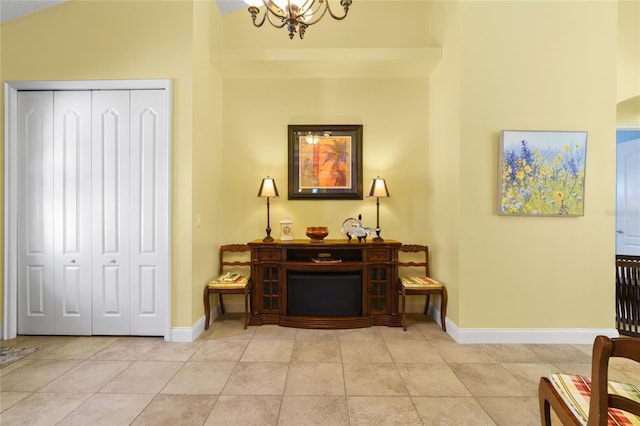 interior space featuring lofted ceiling, light tile patterned flooring, baseboards, and a chandelier