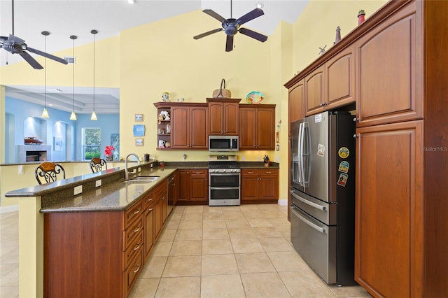 kitchen with a sink, a peninsula, appliances with stainless steel finishes, light tile patterned floors, and ceiling fan