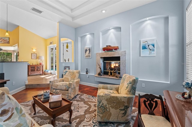 living room with visible vents, a multi sided fireplace, baseboards, and wood finished floors