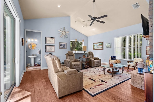 living room featuring wood finished floors, baseboards, a ceiling fan, visible vents, and high vaulted ceiling