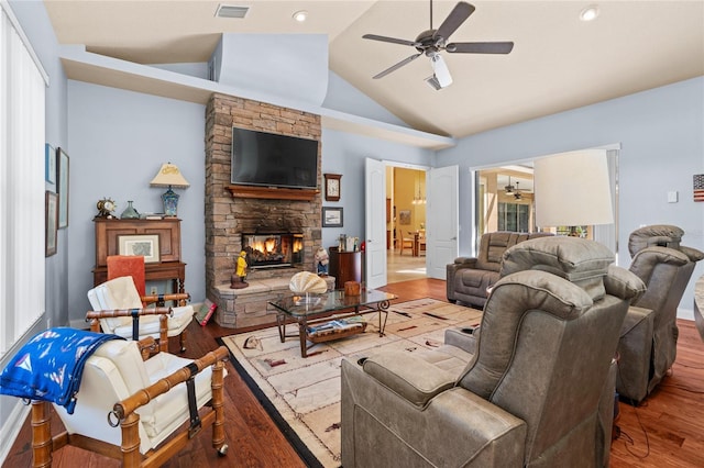 living room with wood finished floors, visible vents, high vaulted ceiling, ceiling fan, and a stone fireplace