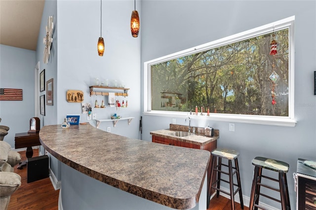 kitchen with dark countertops, decorative light fixtures, dark wood-style floors, and a sink