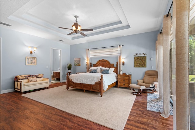 bedroom with multiple windows, a raised ceiling, and wood finished floors