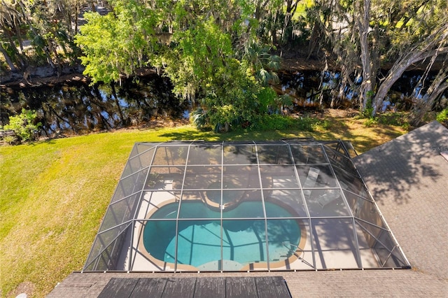 outdoor pool featuring glass enclosure, a lawn, and a patio