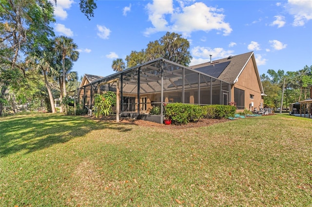 rear view of property with roof mounted solar panels, a lawn, and a lanai