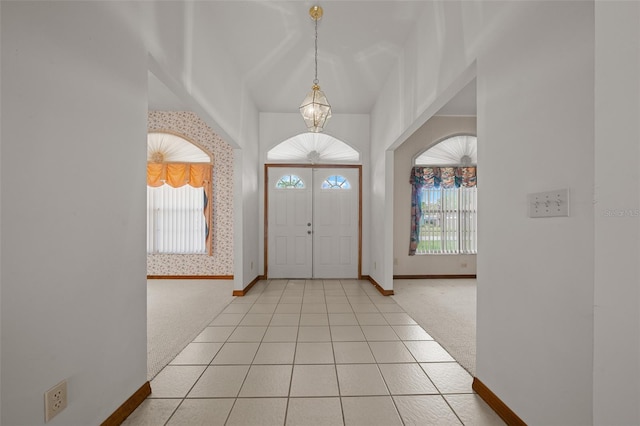 foyer entrance featuring light carpet, an inviting chandelier, wallpapered walls, light tile patterned floors, and baseboards