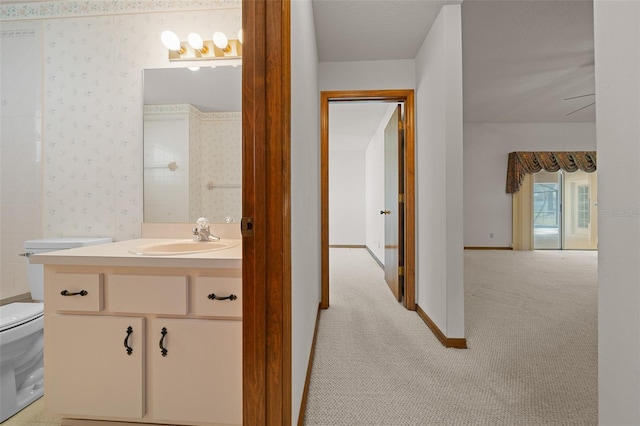 bathroom featuring wallpapered walls, toilet, vanity, and baseboards