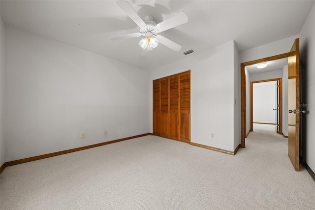 unfurnished bedroom featuring light colored carpet, visible vents, a closet, and baseboards