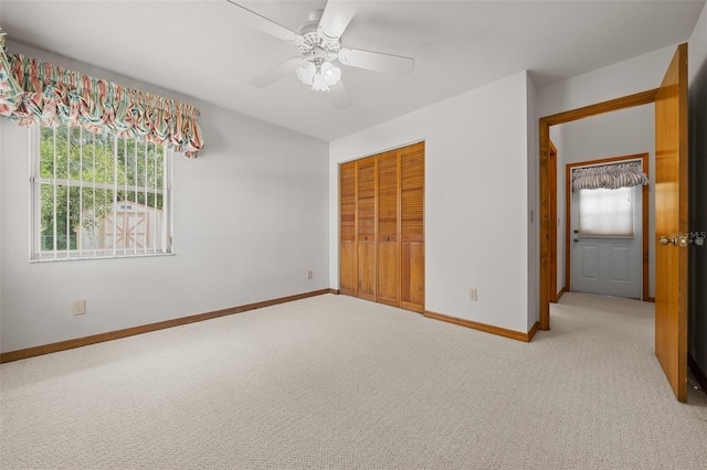 unfurnished bedroom with a closet, light colored carpet, baseboards, and ceiling fan