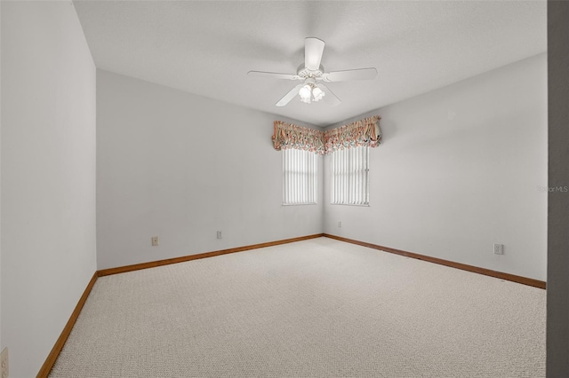 carpeted spare room featuring baseboards and ceiling fan