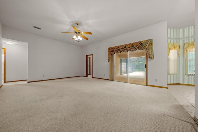 carpeted spare room with visible vents, baseboards, and ceiling fan